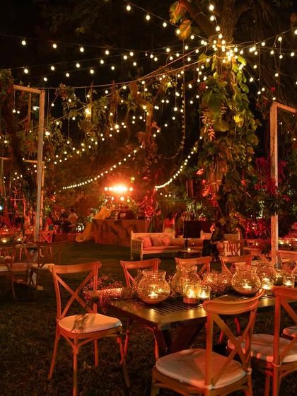 Another perspective of the magical Lohri garden party. The combination of overhead string lights, warm red ambient lighting, and beautifully set tables creates a festive and inviting scene.