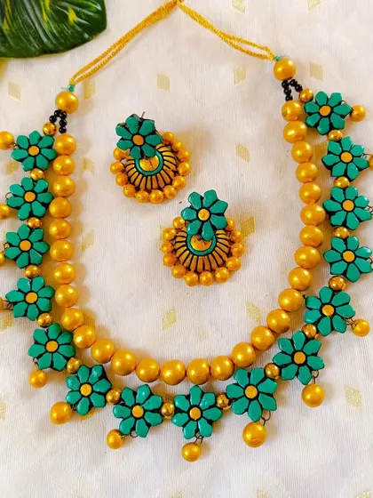 The same floral necklace design in a beautiful sea-green and gold combination. The colors are rich and elegant, perfect for festive wear.