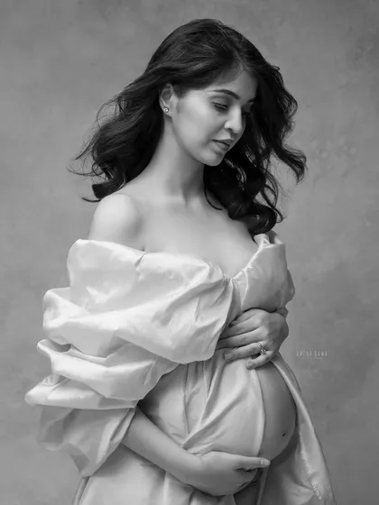 A close-up portrait where black and white conversion emphasizes the soft textures of the silk gown and the gentle movement in her hair.