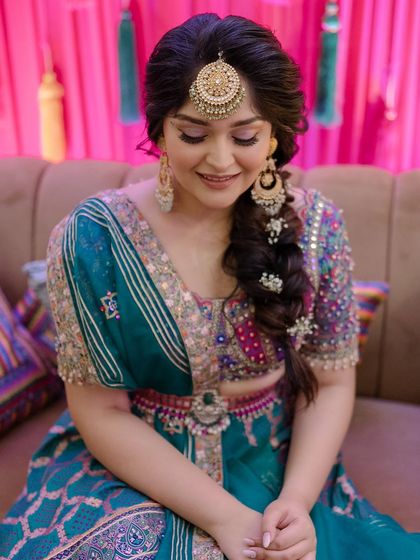 A close-up of the bride with her side braid, showing how it complements her Maang Tikka and colorful outfit.