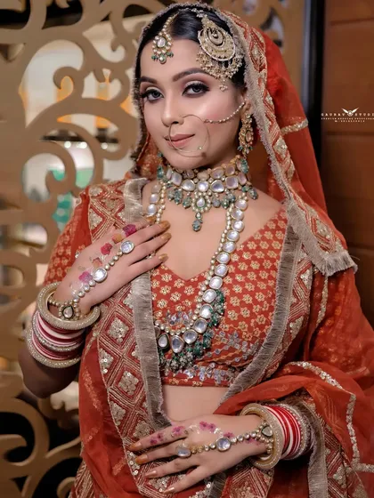 A mid-shot of the bride, highlighting the hand jewelry and the rich embroidery of her blouse.