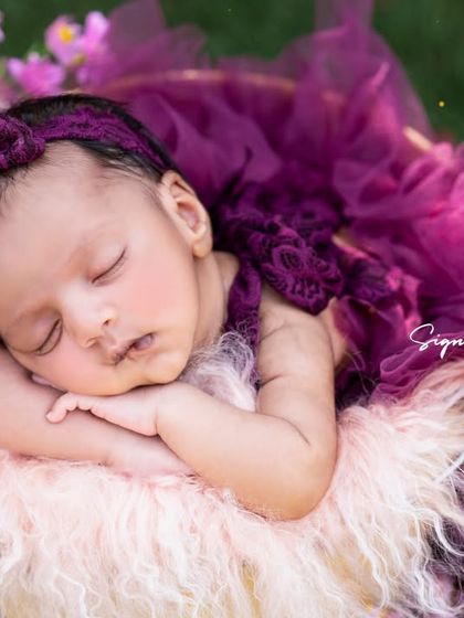 A close-up of the newborn sleeping in her floral outdoor nest, showcasing the peacefulness and beauty of nature-inspired photography.