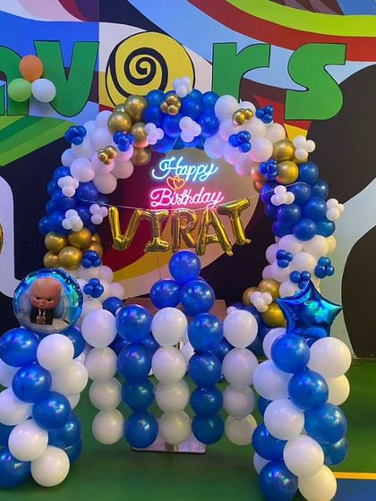 A Boss Baby themed birthday arch with a neon sign. This setup in blue, white, and gold is perfect for a stylish 9th birthday party.