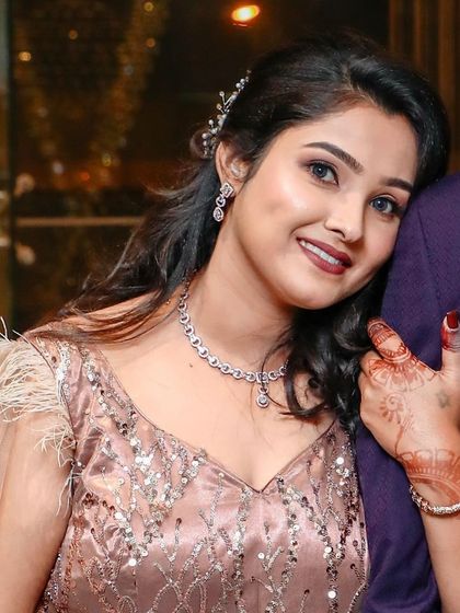A sweet, candid moment from a reception. The bride's makeup is soft and glowing, with a beautiful red lip that complements her blush-toned dress.