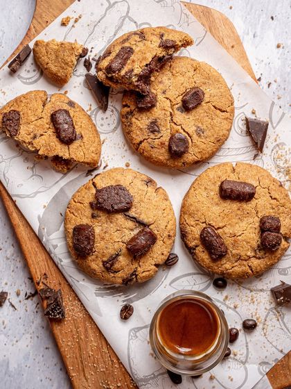 A flatlay of freshly baked chocolate chunk cookies. The scattered crumbs and coffee beans create a rustic, homemade feel. This top down shot is great for showing texture and context.