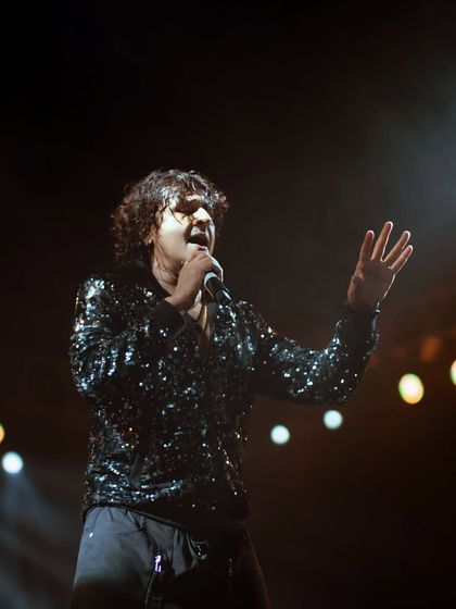 A mid-performance shot of Sonu Nigam, capturing the intensity in his expression. The out-of-focus background lights help to draw all the attention to the artist himself.