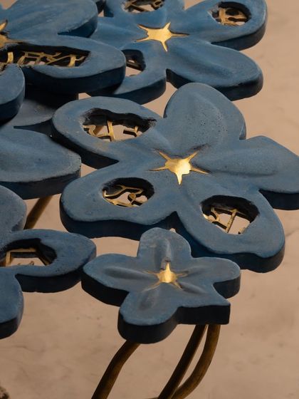 A close-up of the Gul Table reveals the intricate details, with golden light shining through the petals. Each flower is a masterpiece, crafted to celebrate the artistry of the natural world in a functional furniture piece.