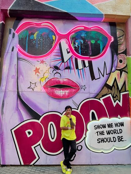 Standing in front of a vibrant, pop-art style mural. The bright colors and energetic art reflect the kind of vibe I bring to my parties.