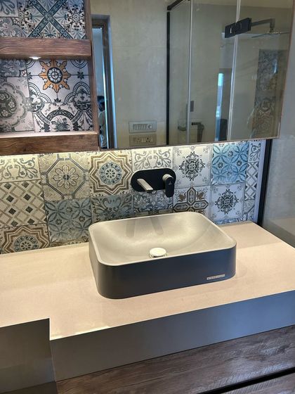 I often use patterned tiles to add character to a space. Here, a backsplash of colorful encaustic tiles provides a vibrant contrast to the modern concrete sink and minimalist black fixtures.