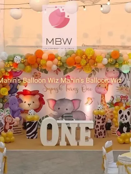 A vibrant jungle-themed first birthday with a backdrop full of cute, illustrated animals. The setup uses animal-print pedestals and a large "ONE" to create a fun and immersive safari experience.