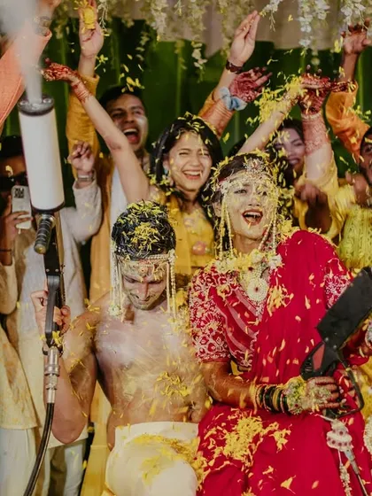 A high-energy moment from a Haldi party, with the couple and guests celebrating with confetti cannons.