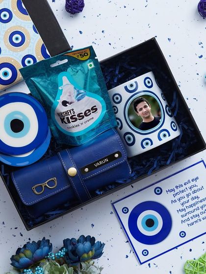 An inside look at the Evil Eye Hamper, showing the personalized mug and other items packed with protective blue-themed shred.