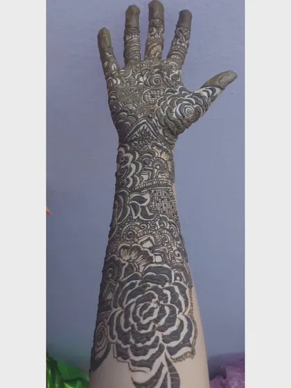 A complete view of a traditional bridal arm design, fresh with paste. Notice the combination of a large rose motif on the forearm with intricate jaali (net) and paisley patterns closer to the hand.