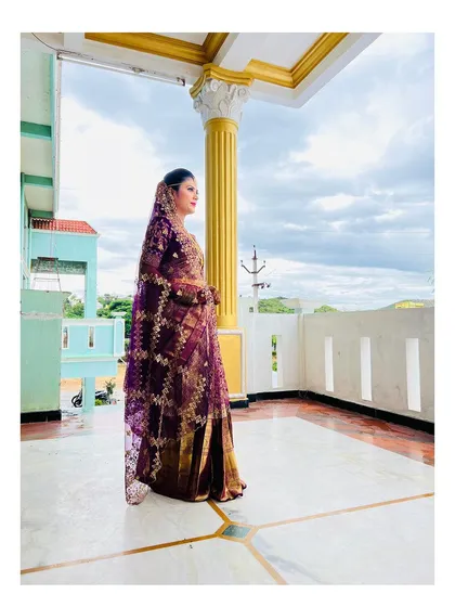 A side profile showcasing the elegant drape of the saree and the intricate details of the bridal look. The makeup is set to be flawless from every angle.