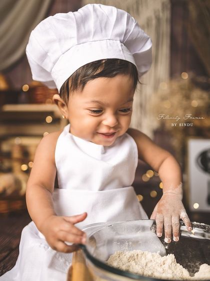 A smiling little chef, happy to be making a mess in his own little kitchen.