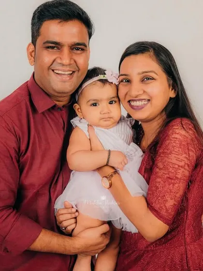 A bright and happy family portrait against a clean white background, showcasing the beautiful bond between parents and their eight-month-old baby girl.
