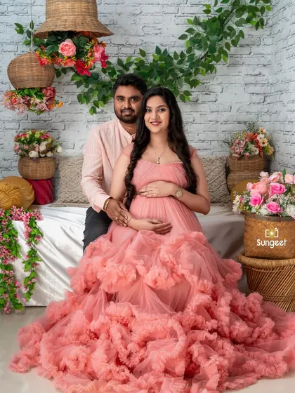 A sweet couple's portrait in a pink ruffled gown, seated in our charming floral-themed setup.