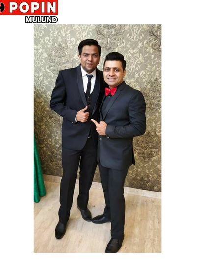 Friends ready for a big night out, both dressed in our formal wear. On the right, a classic black suit with a red bow tie, showing how accessories can personalize a look.
