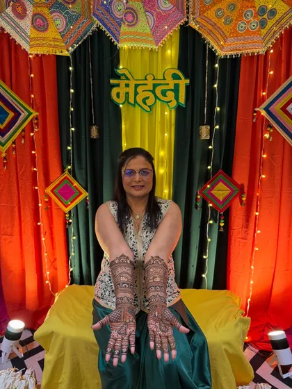 The groom's mom deserves her moment to shine too. Here she is, looking beautiful with her full-hand traditional mehendi against a vibrant backdrop.