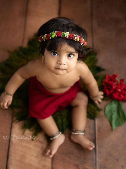 Seven-month-old Monishka sitting up proudly. The simple red wrap and floral headband add a touch of color to this milestone portrait.
