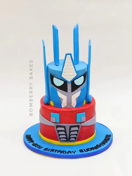 A sculpted two-tier cake designed to look like a Transformer's head, perfect for a robot-themed party.