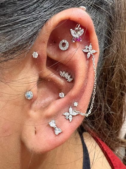 This intricate silver stack is a work of art. It features a chained double stud, a floral helix piece, an evil eye stud, and other delicate pieces for a full and detailed curation.