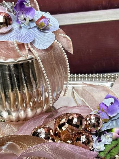 Detail is everything in our luxury gifting. This close-up shows a silver keepsake box on a tray, decorated with delicate pearls, organza ribbons, and a mix of silk flowers and metallic baubles for a baby girl's hamper.