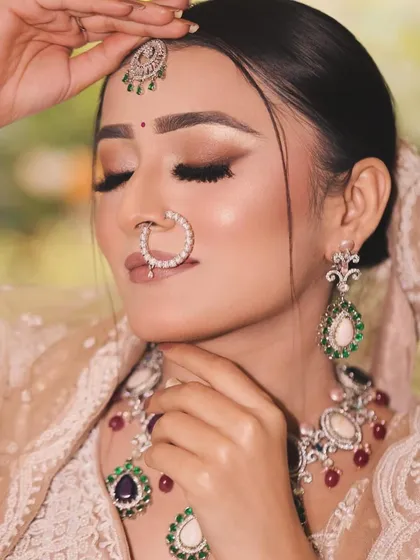 This bride's look is the epitome of modern elegance. The soft brown smokey eye and nude lip are paired with stunning polki and emerald jewelry for a sophisticated finish.