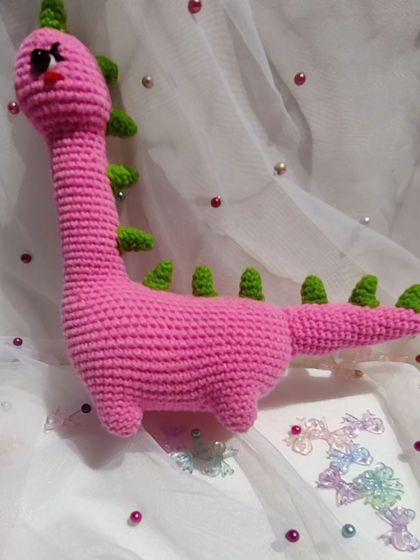 Meet Mrs. Dino, a lovely pink dinosaur with green spikes.