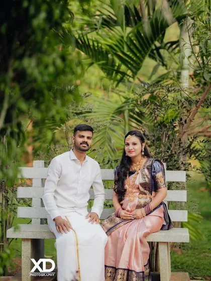 A serene portrait of a couple seated on a park bench, dressed in elegant traditional clothing.