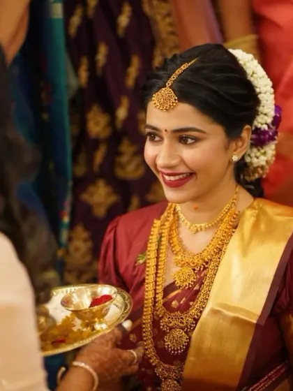 A happy bride during her wedding. Her bright smile and bold red lip are the perfect complements to her traditional gold jewelry and silk saree.