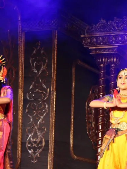 Two of our dancers in a moment of quiet devotion during the "Nava Durga" performance. The intricate details of their costumes and the grand stage set are visible here.