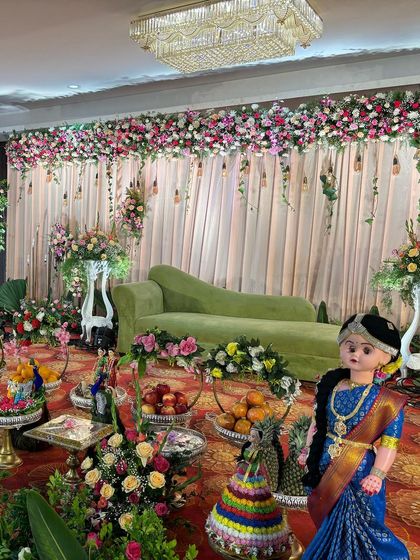 A stage with a soft green sofa and a backdrop of pink curtains and hanging light bulbs.