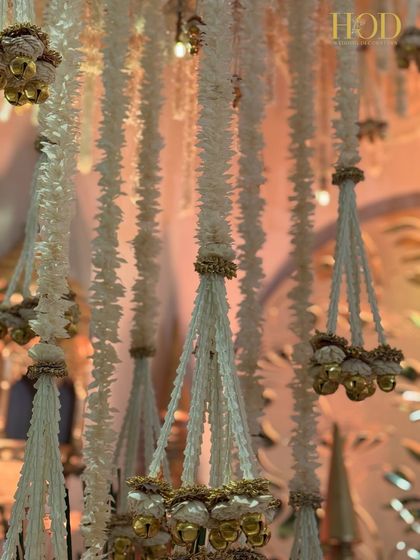 A macro shot of the hanging floral tassels, highlighting the texture of the flowers and the tiny golden bells.