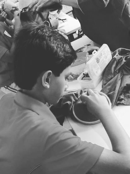 A student practices his stitching on a piece of fabric using an embroidery hoop. Learning to control the needle and thread is the first step towards mastering the art of mending.