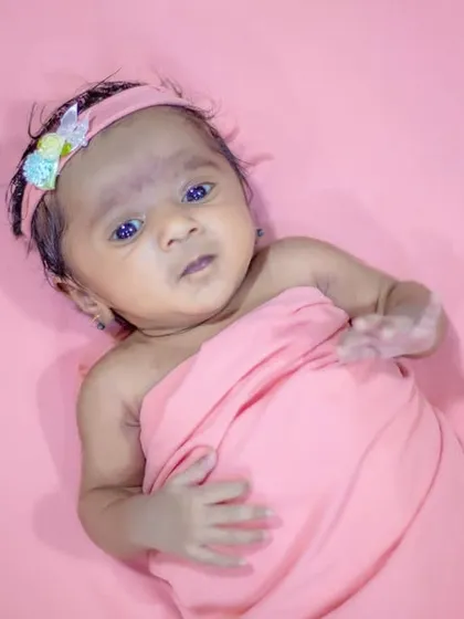 Capturing a sweet, awake moment during a newborn session. This little one is wrapped comfortably on a simple pink backdrop, allowing her expressive face to be the focus.