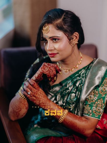 A portrait of a bride in a green and red half-saree, capturing her beautiful smile and traditional look.