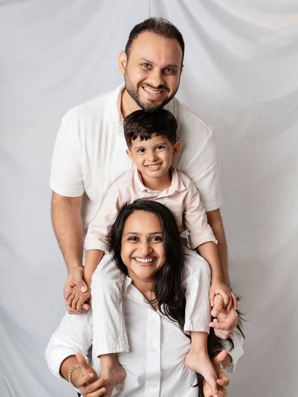Another creative family pose, this time with the son sitting on his mother's shoulders while the father stands behind.