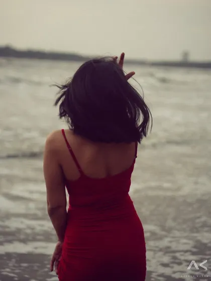 A collection of portraits featuring a model in a red dress on the rocks and by the water. The series explores different poses and moods, from serene to powerful.