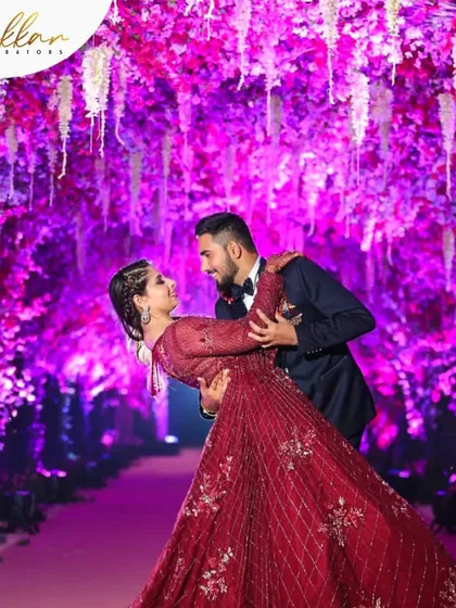A couple shares a dance under a stunning floral tunnel lit in a vibrant purple hue. I design these immersive environments to create truly magical photo opportunities.