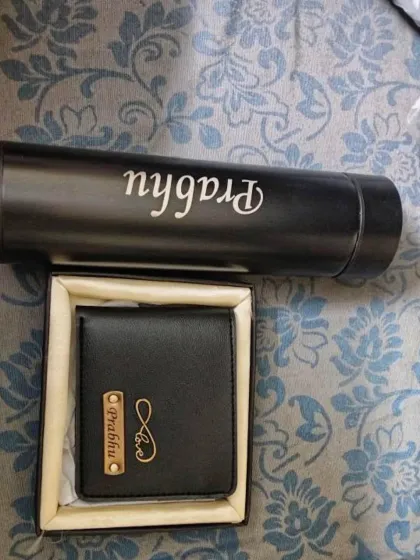 A customer's photo of their personalized black leather wallet and matching name-engraved flask.
