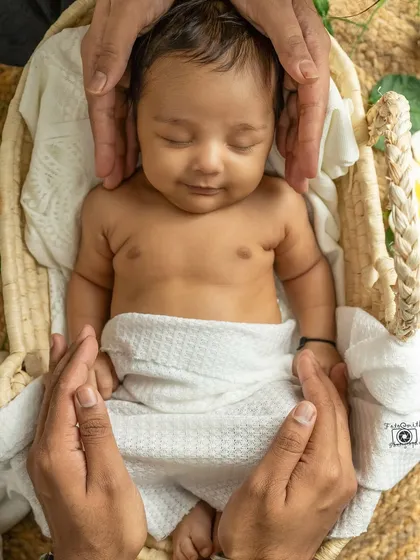 A beautiful composition of parents' hands framing their smiling, sleeping baby. This "hands-on" shot is a symbol of love and protection.