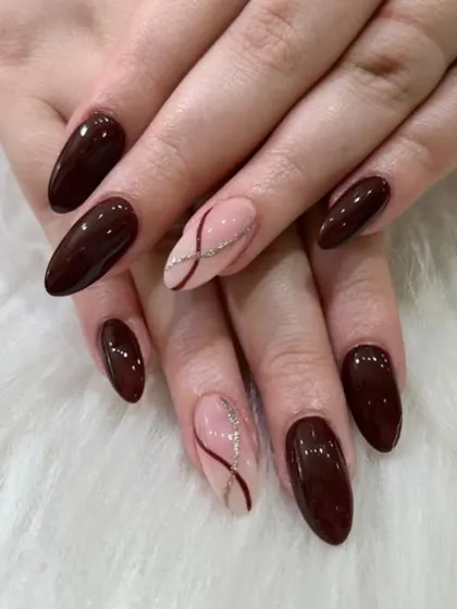A sophisticated and warm set with deep brown nails and sheer accent nails featuring delicate, intersecting glitter lines.