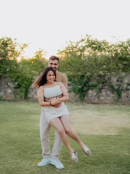 A playful and fun moment during a sunset shoot in a park, with the groom lifting his bride-to-be.