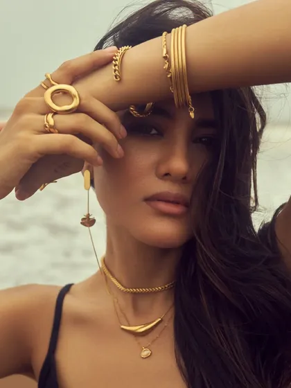 This pose highlights the bracelets and necklaces. The makeup look is all about a healthy, radiant glow.