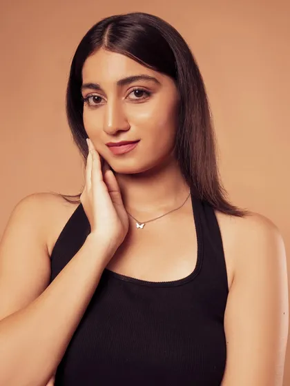 A simple, elegant portrait in a black dress. The warm, tan background complements the skin tone beautifully.