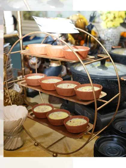 A display of traditional Indian desserts like Phirni, served in earthy clay pots on an elegant copper stand. It's a perfect sweet ending for any festive meal or wedding event.