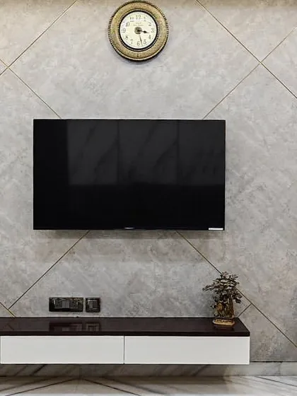 The TV wall in this master bedroom is designed with a subtle concrete texture and geometric grooves. A floating console and a sleek study corner complete this functional and stylish space.