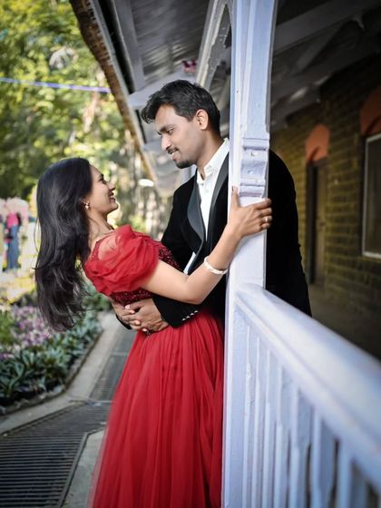 A sweet, romantic moment captured during a pre-wedding shoot. The classic red gown and black blazer create a timeless look.