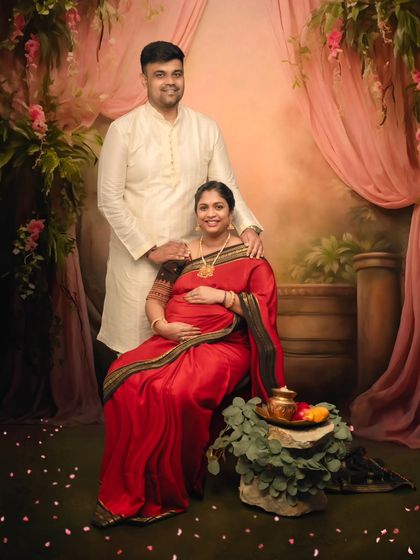A full-setting portrait of a couple in a painterly, romantic scene, complete with flowers, drapery, and traditional offerings.